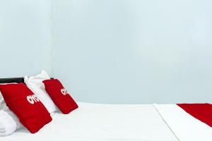 a bed with red and white pillows on it at OYO 91720 Hotel Yotowawa in Kupang