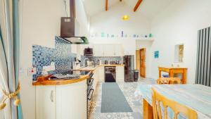 una cocina con armarios blancos y azulejos azules en Peibio at Llanfair Hall en Dwyran