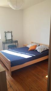a bedroom with a bed with blue sheets and orange pillows at Les chambres de la tribu in Curgy