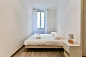 a white bedroom with a bed and a window at CMG - Bel appartement - 5 min à pied du Palais des Festivals in Cannes