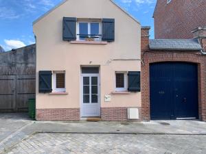 una casa con puertas azules y una valla en Le Cocon des Hortillonnages d'Amiens, en Camon
