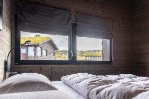 a bedroom with two windows with a bed and a house at Mosetertoppen Skiline - Hafjell Ski Resort in Øyer