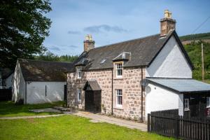 una antigua casa de piedra con techo negro en Lock Keepers Cottage, Loch Ness Cottage Collection en Inverness