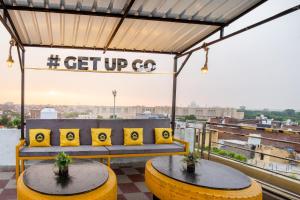 a patio with two tables and a bench on a roof at The Hosteller Agra in Agra