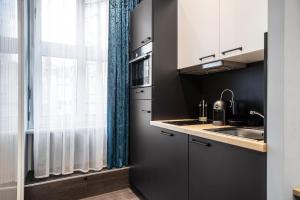 a kitchen with white cabinets and a sink and a window at Aparthotel by dasPaul in Nuremberg