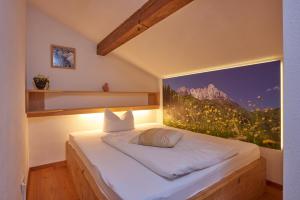 Bett in einem Zimmer mit einem großen Fenster in der Unterkunft Gästehaus Bergstüberl in Reit im Winkl