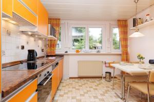 eine Küche mit orangefarbenen und weißen Schränken und einem Tisch in der Unterkunft Fewo Röspe in Erndtebrück