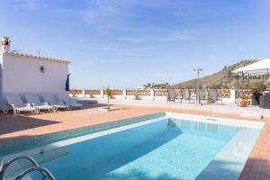 a swimming pool on a patio with chairs and a building at Villa Benama in Torrox