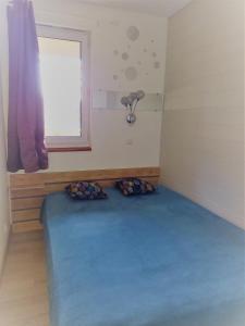 una camera con letto blu in una stanza con finestra di Charmant logement sur la station de Val Louron a Val-Louron