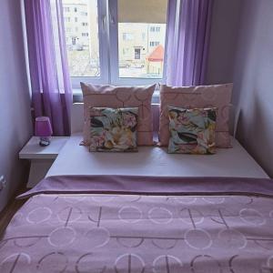 a bed with pillows and a window with purple curtains at LesnApart in Hel