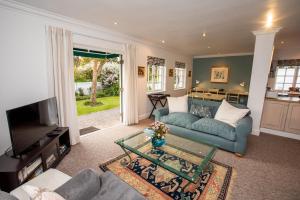 a living room with a blue couch and a tv at Greenhill Farm Cape Dutch Cottage Plettenberg Bay - 1 Bedroom Private Cottage in Plettenberg Bay