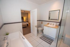 a bathroom with a tub and a sink and a toilet at Greenhill Farm Cape Dutch Cottage Plettenberg Bay - 1 Bedroom Private Cottage in Plettenberg Bay +33 photos