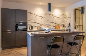 a kitchen with a counter and two bar stools at ApartHotel Boutique by Urban Home Stay in Alkmaar