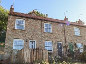 a brick house with a wooden fence in front of it at Honeybee Cottage in Ripon