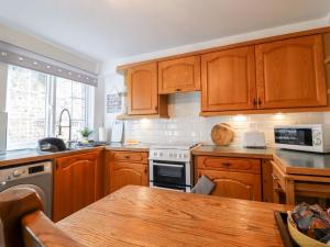 uma cozinha com armários de madeira e uma mesa de madeira em Honeybee Cottage em Ripon