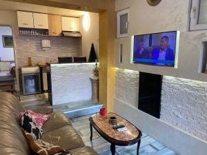 een woonkamer met een bank en een tv aan een bakstenen muur bij Apartment Lux Belgrade in Belgrado