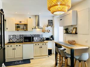 a kitchen with white cabinets and a table with chairs at Joli studio cosy in Châteaubriant