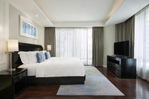 Schlafzimmer mit einem Bett und einem Flachbild-TV in der Unterkunft Dusit Suites Hotel Ratchadamri, Bangkok in Bangkok