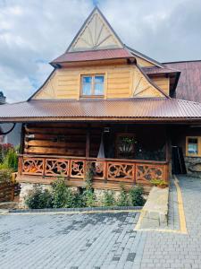 a large wooden house with a fence in front of it at Apartament na Uboczu. in Kościelisko