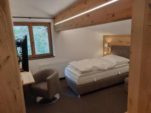 a bedroom with a bed and a tv and a chair at Hotel Garni Viktoria in Sankt Anton am Arlberg