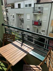 uma mesa de madeira e 2 cadeiras numa varanda em Vert Cozy Apartment Free Parking em Novi Sad