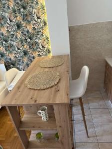 uma mesa de madeira com duas cadeiras e uma caneca de café em Vert Cozy Apartment Free Parking em Novi Sad