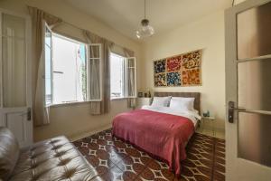 um quarto com uma cama com um cobertor vermelho e 2 janelas em Homey 2BR Apt w Private Balcony in City Center by Sea N' Rent em Tel Aviv
