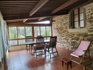 a dining room with chairs and a table and windows at Casa Rural A Telleira in A Estrada