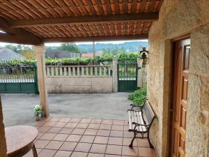 a patio with a bench and a wooden pergola at Casa Rural A Telleira in A Estrada