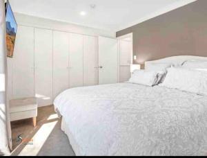 a white bedroom with a large bed and a window at Stylish Thredbo Alpine Chalet + Garage in Tranquil Setting in Thredbo