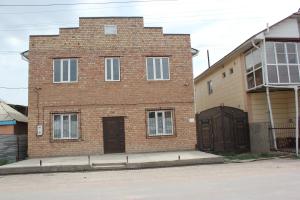 un edificio de ladrillo con dos puertas y un garaje en Uz-Anar Guest House, en Kochkorka