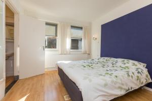 1 dormitorio con cama y pared azul en Holidayhouse - Oranjeplein 23 Zoutelande, en Zoutelande