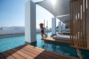 a woman is standing on the edge of a swimming pool at Manoula's Beach Mykonos Resort in Agios Ioannis Mykonos