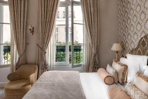 a bedroom with a bed and a chair and a window at Relais Christine in Paris +37 photos