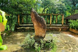 a stone statue in a garden with a bench at Rainforest Edge in Kalawana
