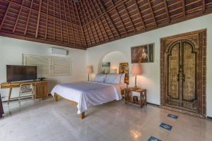 a bedroom with a bed and a flat screen tv at Bali Villa Home in Seminyak