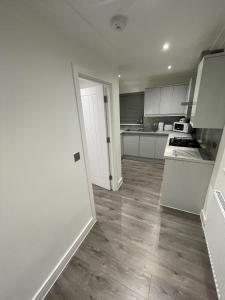 una cocina vacía con armarios blancos y suelo de madera en London West Ham Apartments en Londres