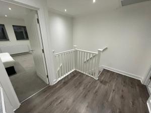 a room with a staircase with white walls and wooden floors at London West Ham Apartments in London