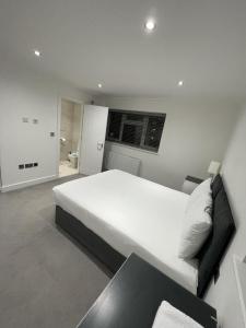 a bedroom with a large white bed and a couch at London West Ham Apartments in London