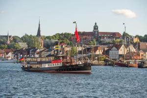 a boat in the water with a city in the background at Ferienappartement Brandenburg in Flensburg +4 photos