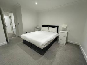 a bedroom with a white bed and two night stands at London West Ham Apartments in London