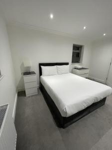 a white bedroom with a large bed with white sheets at London West Ham Apartments in London