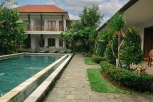 un patio trasero con piscina y una casa en Green Papaya House, en Ubud