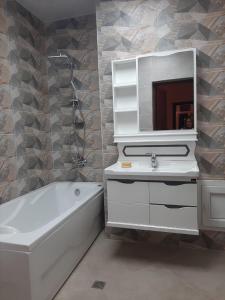 a bathroom with a tub and a sink and a mirror at My sweet home in Qara Qarayev in Baku