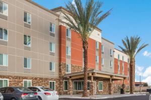 an apartment building with palm trees in front of it at WoodSpring Suites Mesa Chandler in Mesa