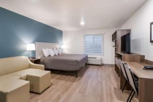 um quarto com uma cama, um sofá e uma televisão em WoodSpring Suites Mesa Chandler em Mesa