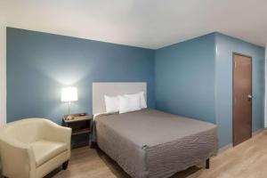 um quarto azul com uma cama e uma cadeira em WoodSpring Suites Mesa Chandler em Mesa
