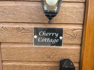 een bord met kersenhuisje op een houten muur bij Cherry Cabin with Hot Tub in York