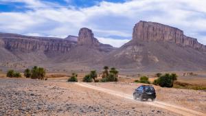 Una macchina che guida su una strada sterrata nel deserto. di Bivouac Dune Iriki a Foum Zguid Altre 17 foto