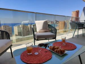 un tavolo con 2 bevande e croissant su un balcone di SUNSET CLIFFS sea view apartments a Benidorm